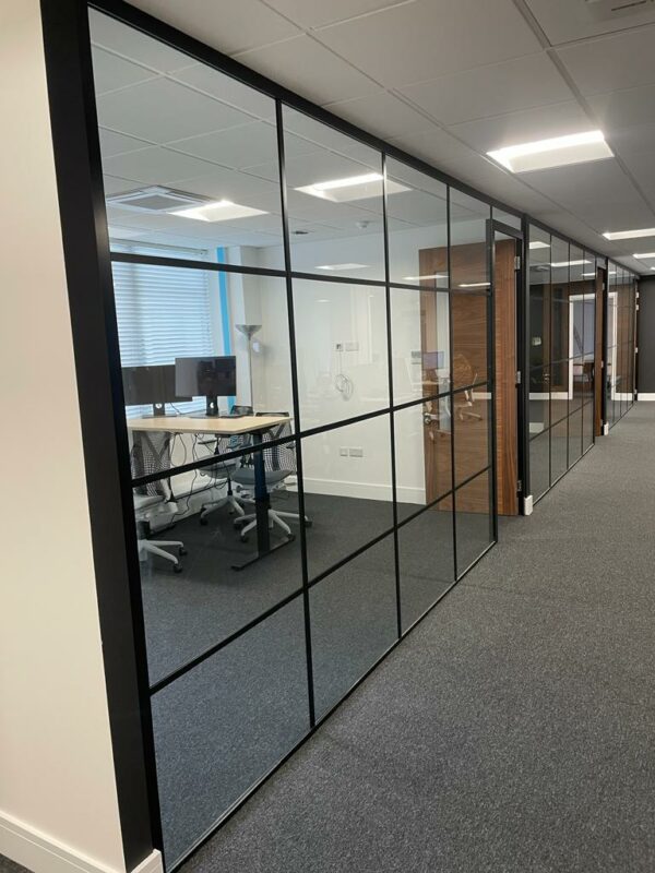 Trendy glass office partition wall using black banding strips creating meeting room area