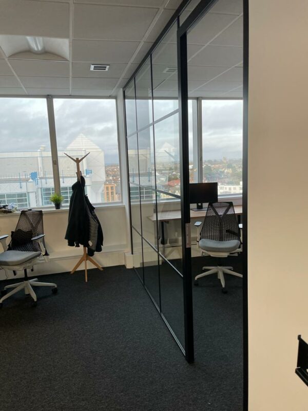 Trendy glass office partitions with black banding strips against window