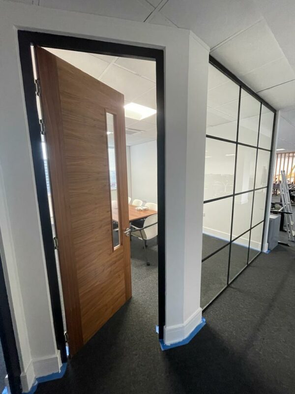 Timber door with black aluminium door frame matching partitions in office setting