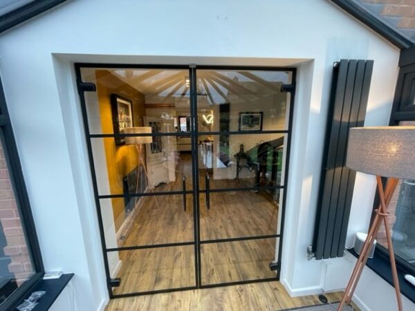 Closed glass door partitions using trendy black crittall banding strips to separate living room