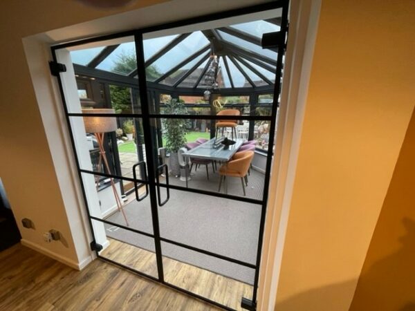 Closed glass door partitions for the home using black crittall banding strips to separate conservatory and lounge