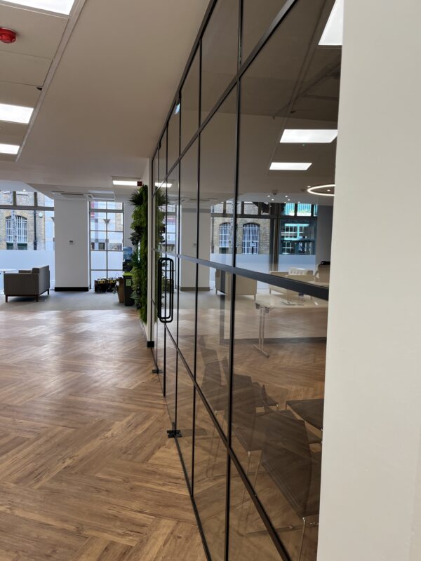 Modern office space with wood flooring and glass demountable office partitions