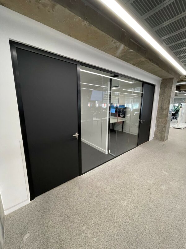 Trendy glass office partitions with black laminated timber door to create meeting room