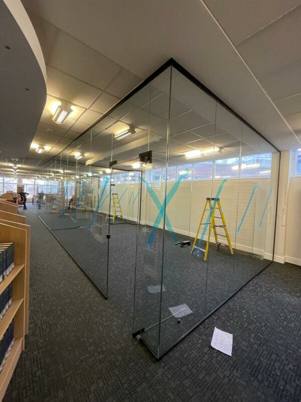Large glass partitioning separating two spaces within an office space.
